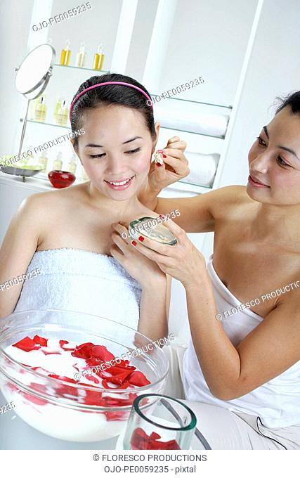 Woman putting cream on other woman at spa