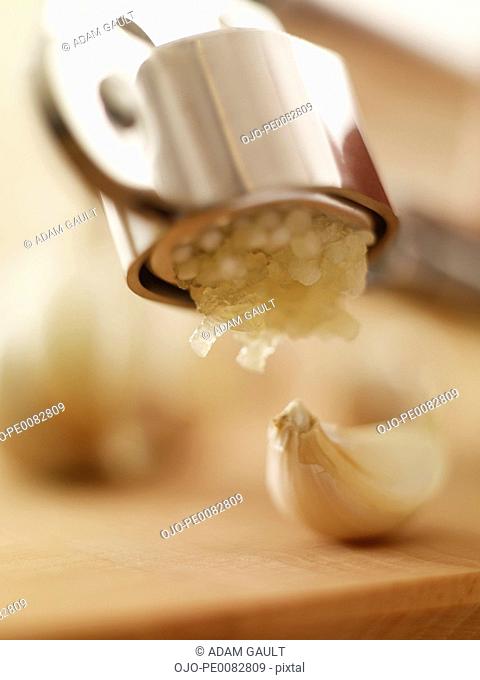 Close up of garlic clove and garlic press