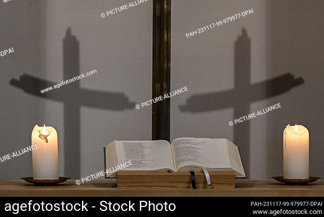 PRODUCTION - 16 November 2023, Berlin: Candles, the Bible and shadows of the cross can be seen in the chapel of St. Elisabeth's Cemetery
