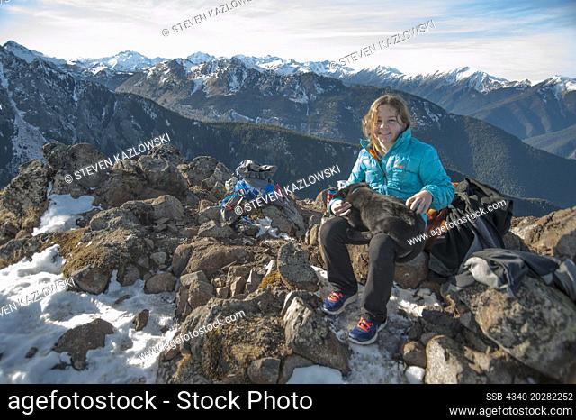 Washington, Olympic Peninsula, northwest Olympic National Park, Mount Townsend. Young girl rests on the summit with a sleepy puppy