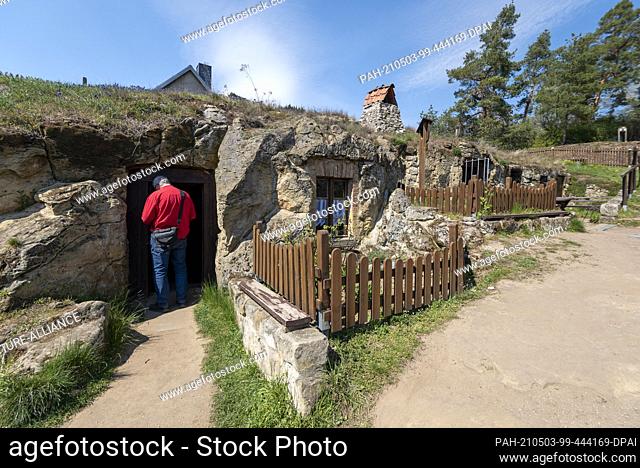28 April 2021, Saxony-Anhalt, Halberstadt: A man stands in front of a cave dwelling on the Schäferberg. The dwellings, carved into the sandstone by migrant...