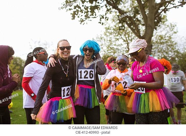 Portrait playful female runners in wigs and tutus at charity run in park