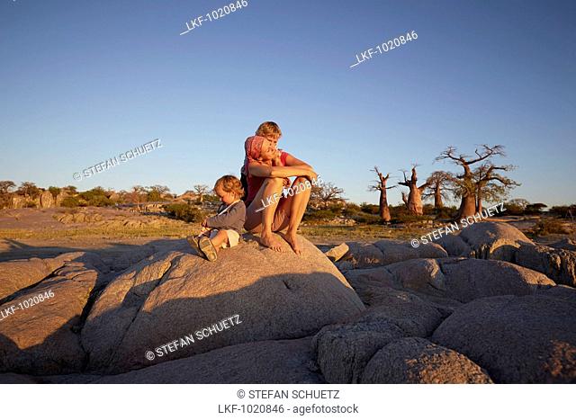 Mother and sons sitting on a rock, Kubu Island, Makgadikgadi Pans National Park, Botswana