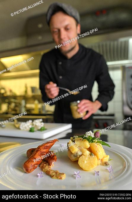 15 May 2020, Brandenburg, Kaisermühl: Sören Horny, cook at Hotel Kaisermühle, prepares a wild garlic sausage with potato caper salad in the kitchen