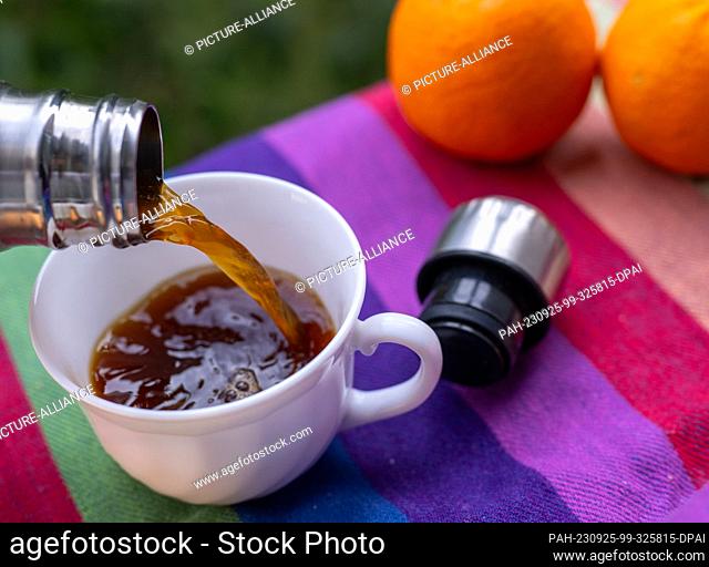 ILLUSTRATION - 18 September 2023, Berlin: Warm coffee flows from a thermos flask into a cup sitting on a picnic blanket. Photo: Monika Skolimowska/dpa