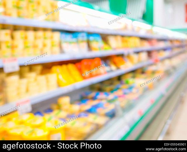 Defocused blur of supermarket shelves with cheese. Blur background with bokeh. Defocused image