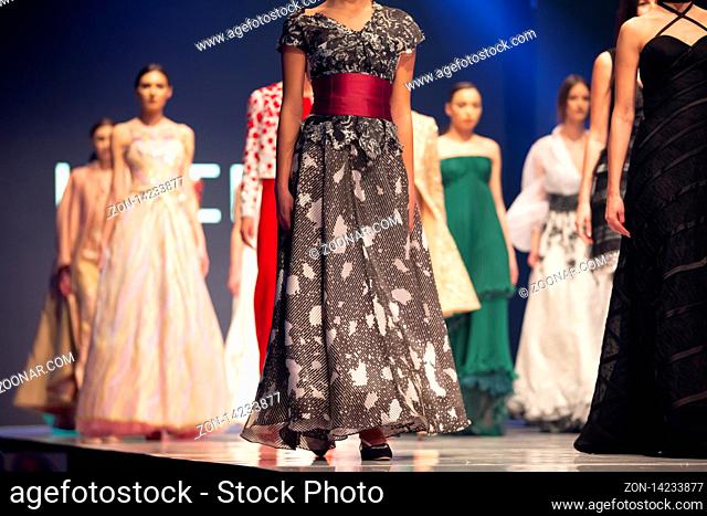 Female models walk the runway in beautiful colorful dresses during a Fashion Show. Fashion catwalk event showing new collection of clothes