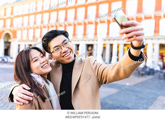 Spain, Madrid, happy young couple taking a selfie in the city