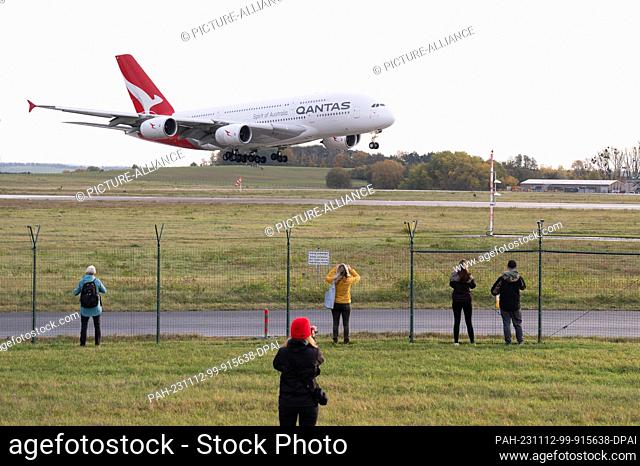 12 November 2023, Saxony, Dresden: Onlookers watch a Qantas Airways Airbus A380 land at Dresden Airport. The aircraft, which had taken off from Sydney
