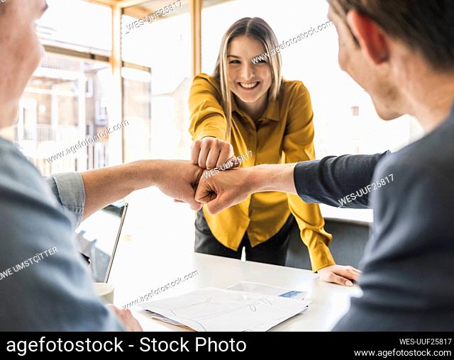 Happy business team touching fists in office