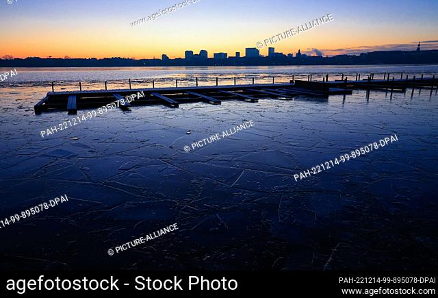 14 December 2022, Hamburg: Thin ice floes float before sunrise on the Alster at the Rabenstraße pier. Photo: Christian Charisius/dpa