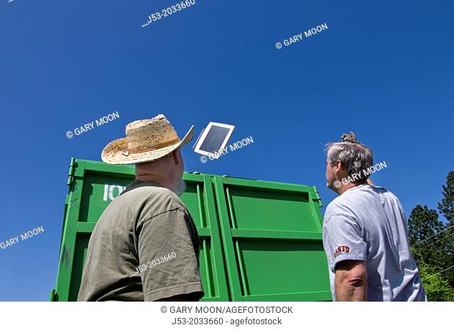 Volunteers throw old monitor into dumpster during community e-waste collection fundraiser in Grass Valley California. All donated electronic items are hauled...
