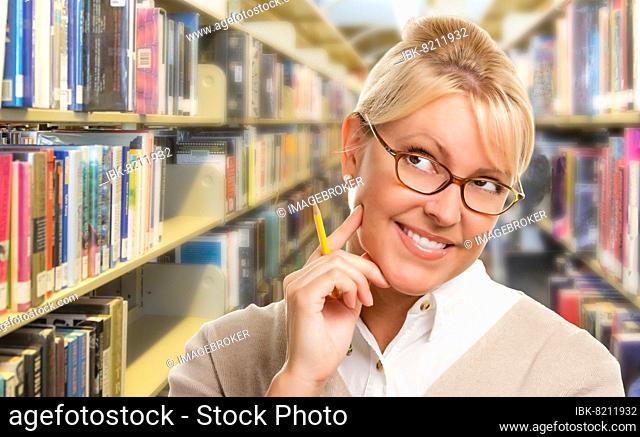 Beautiful expressive student or teacher with pencil in library