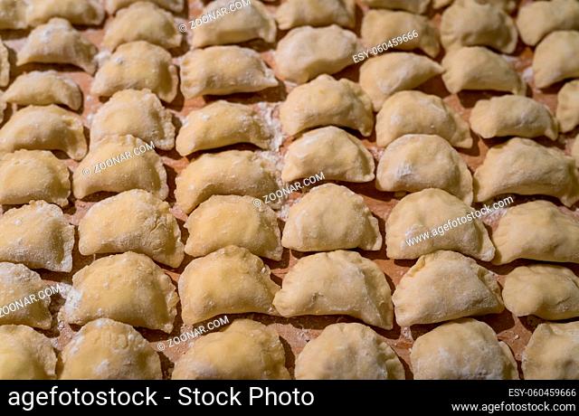 Traditonal Polish food called pierogi, similar to italian ravioli, freshly rolled in dough and drying on the kitchen table, ready to be cooked