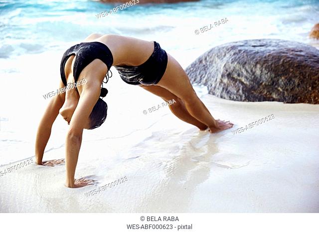 Seychelles, woman bridge position at seafront