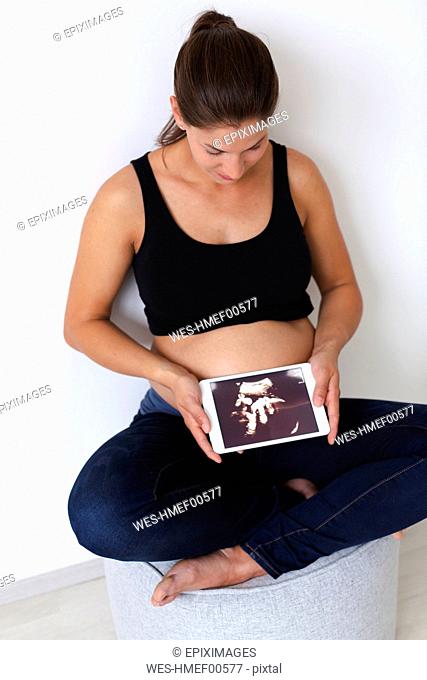 Young pregnant woman with ultrasound image on her tablet of her unborn baby