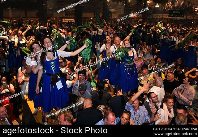 03 October 2023, Bavaria, Munich: Waiters and waitresses celebrate the end of the Wiesn with guests at the traditional Kehraus in the Hofbräuzelt