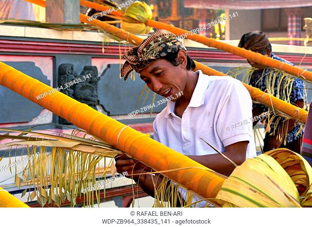 BALI - JULY 28 2019:Balinese men preparing Traditional Bali Penjor bamboo pole with decoration in a temples in Bali Indonesia on Galungan Kuningan holidays