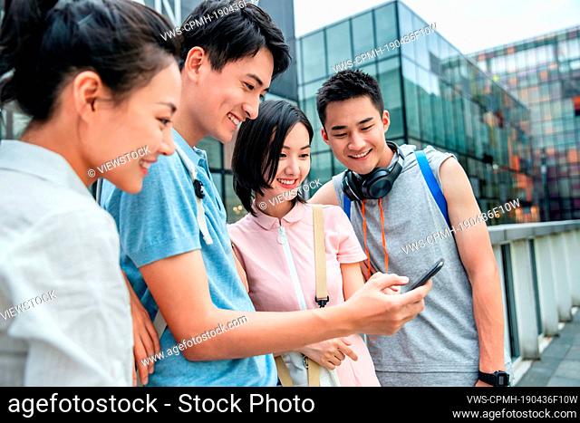 Outdoor four college students watch mobile phone