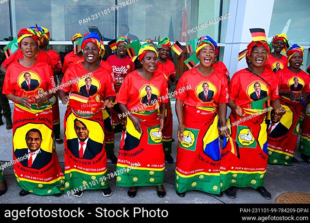 01 November 2023, Zambia, Lusaka: Women in colorful clothes with the likeness of President Hichilema sing and dance with military honors at Kenneth Kaunda...