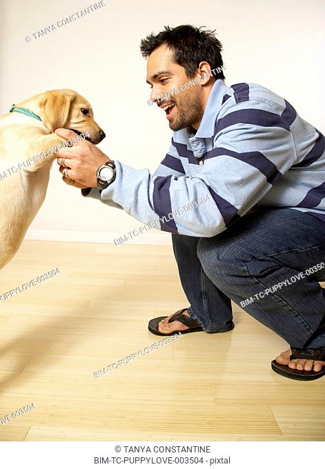 Mixed Race man playing with puppy dog