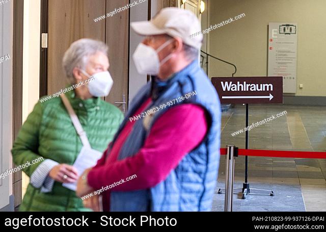 23 August 2021, Lower Saxony, Hanover: A sign ""Wahlraum"" stands in the New Town Hall while a couple waits for their voting documents to be handed out