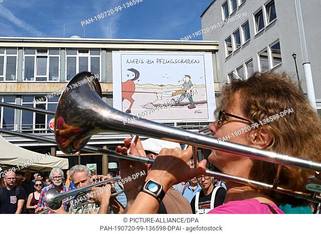 20 July 2019, Hessen, Kassel: During a demonstration against the march of the small party ""Die Rechte"" in front of a big cartoon in front of the Caricatura
