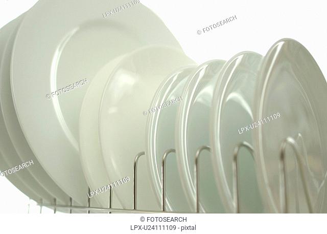 Clean plates on dish rack, close up, white background