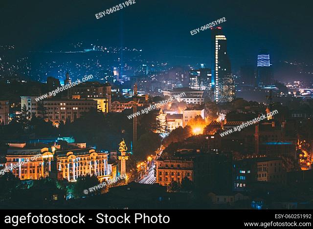 Tbilisi, Georgia. Construction Development Of Modern Architecture On Background Of Urban Night Cityscape. Evening Night Scenic Aerial View Of City Center