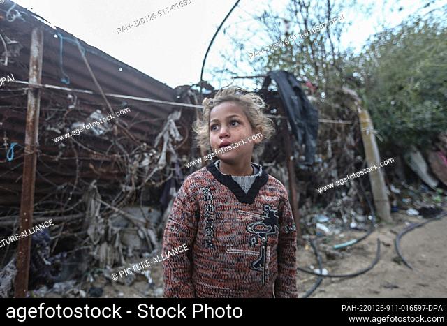 26 January 2022, Palestinian Territories, Beit Lahia: A Palestinian child stands in front of her house during the cold weather of the winter season in the...