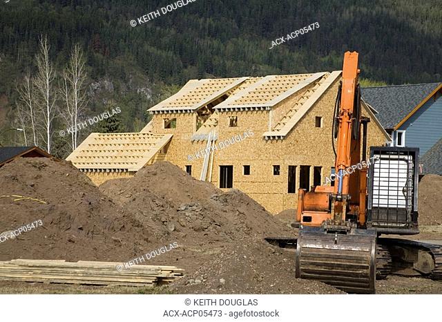 Excavator and new homes at subdivision, Smithers, British Columbia, Canada