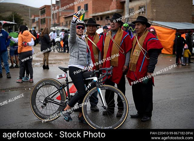 09 April 2022, Bolivia, Jankho Amaya: A cyclist takes a selfie with local authorities before the bike race. The ""Poncho rojo"" (red poncho) race attracts both...