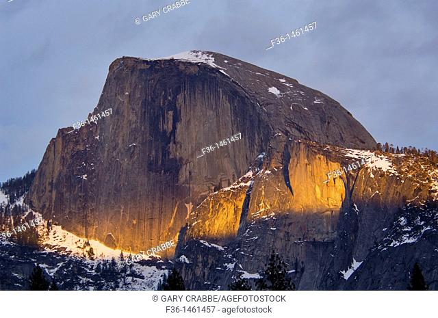 Narrow band of sunset light through spring storm clouds on the face of Half Dome, Yosemite National Park, California
