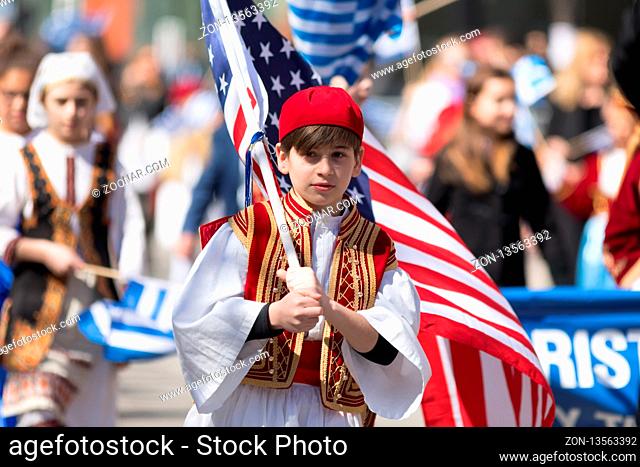 Chicago, Illinois, USA - April 29, 2018 Greek Children wearing traditional clothing and carrying the USA flag during the Greek Independence Day Parade