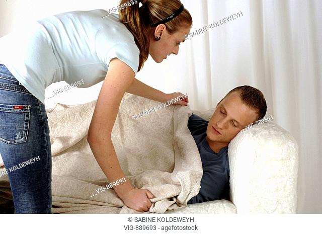 Young woman carpets her sleeping boyfriend on a sofa. - 30/06/2008