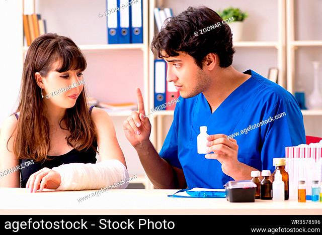 Young woman with bandaged arm visiting male doctor traumotologist