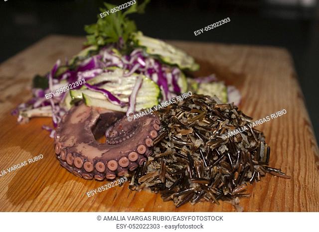 Wild rice accompanied by tentacle of octopus and salad of cucumber and purple cabbage
