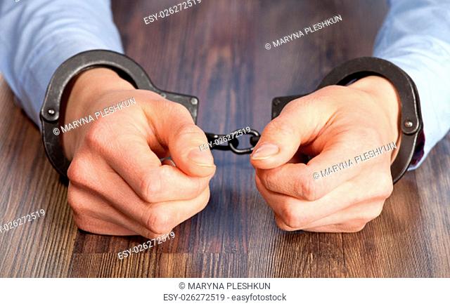 Hands in handcuffs on the table