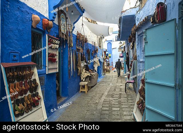 Various items for sale hanging on blue wall at alley, Chefchaouen, Morocco