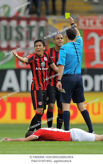 Referee Frankfurt's Manuel Gräfe (front, back view) shows Frankfurt's Bamba Anderson (L) the yellow card as his teammate Makoto Hasebe tries to appease and...
