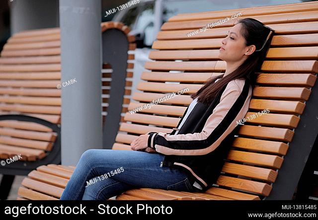 Pretty Asian girl sits on a bench and relaxes - people photography