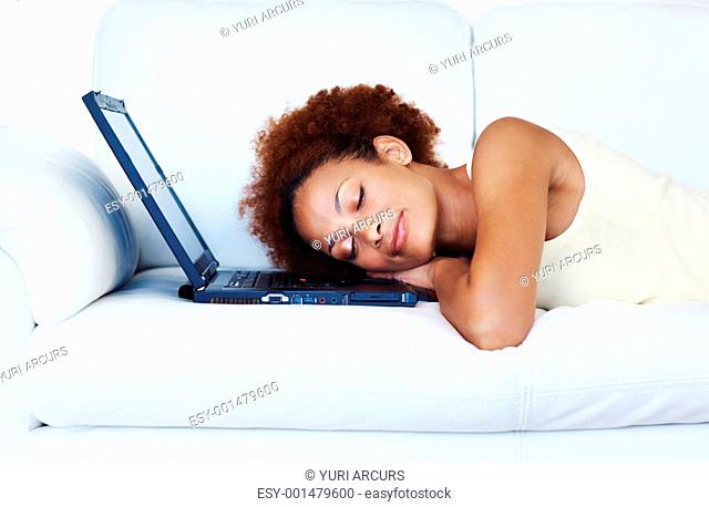 African American female asleep on laptop on sofa at home