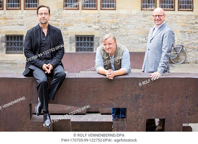 Actors Jan Josef Liefers (l) and Axel Prahl as well as the Mayor of Muenster Markus Lewe (r, CDU) pose on two benches by artist Eduardo Chillida during the...