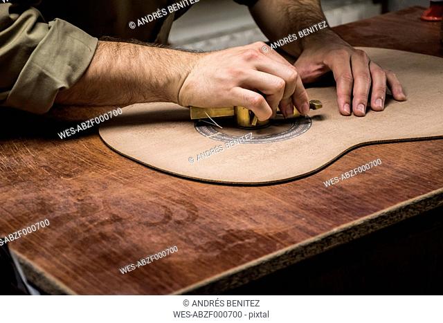 Luthier manufacturing a guitar in his workshop, close-up