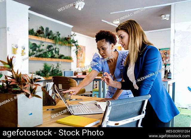 Businesswomen discussing over laptop in office