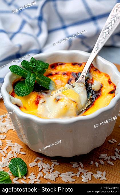 Turkish traditional milk rice pudding (sutlac) is served in a ceramic form on a wooden board, selective focus
