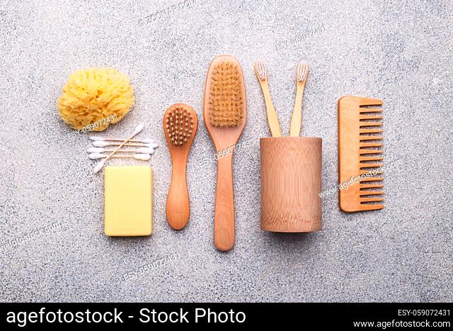 Zero waste reusable bathroom items on natural stone background, wooden comb, tooth brush, sea sponge, ear sticks, solid soap, flat lay
