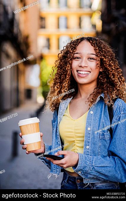Curly haired woman with reusable cup in city
