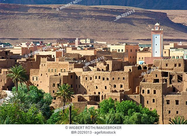 Oasis village, decaying kasbahs, mud fortresses, residential castles of the Berber tribe with modern houses and mosque with minaret at back, Tinerhir