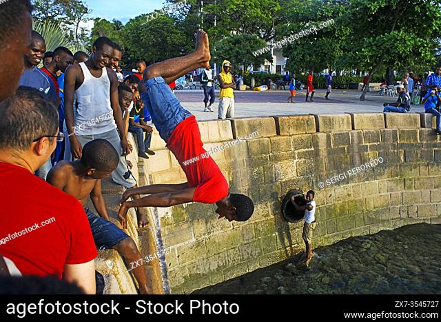 Local boys jumping off the Malecon into the sea next to the pier in Stone Town, Zanzibar, Tanzania